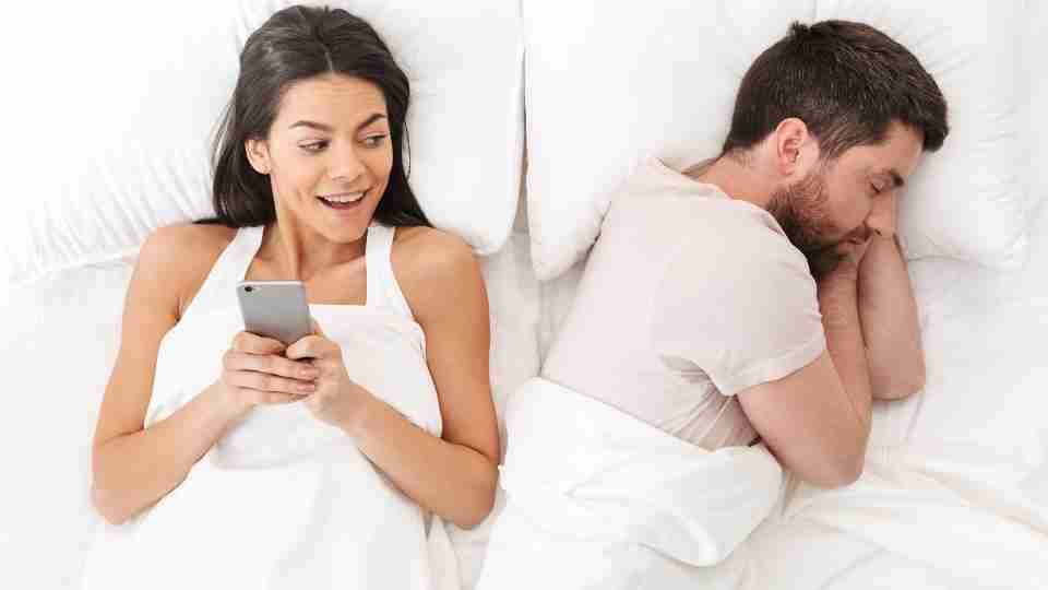 Cheating wife discreetly texting beside sleeping husband in Salt Lake, Utah